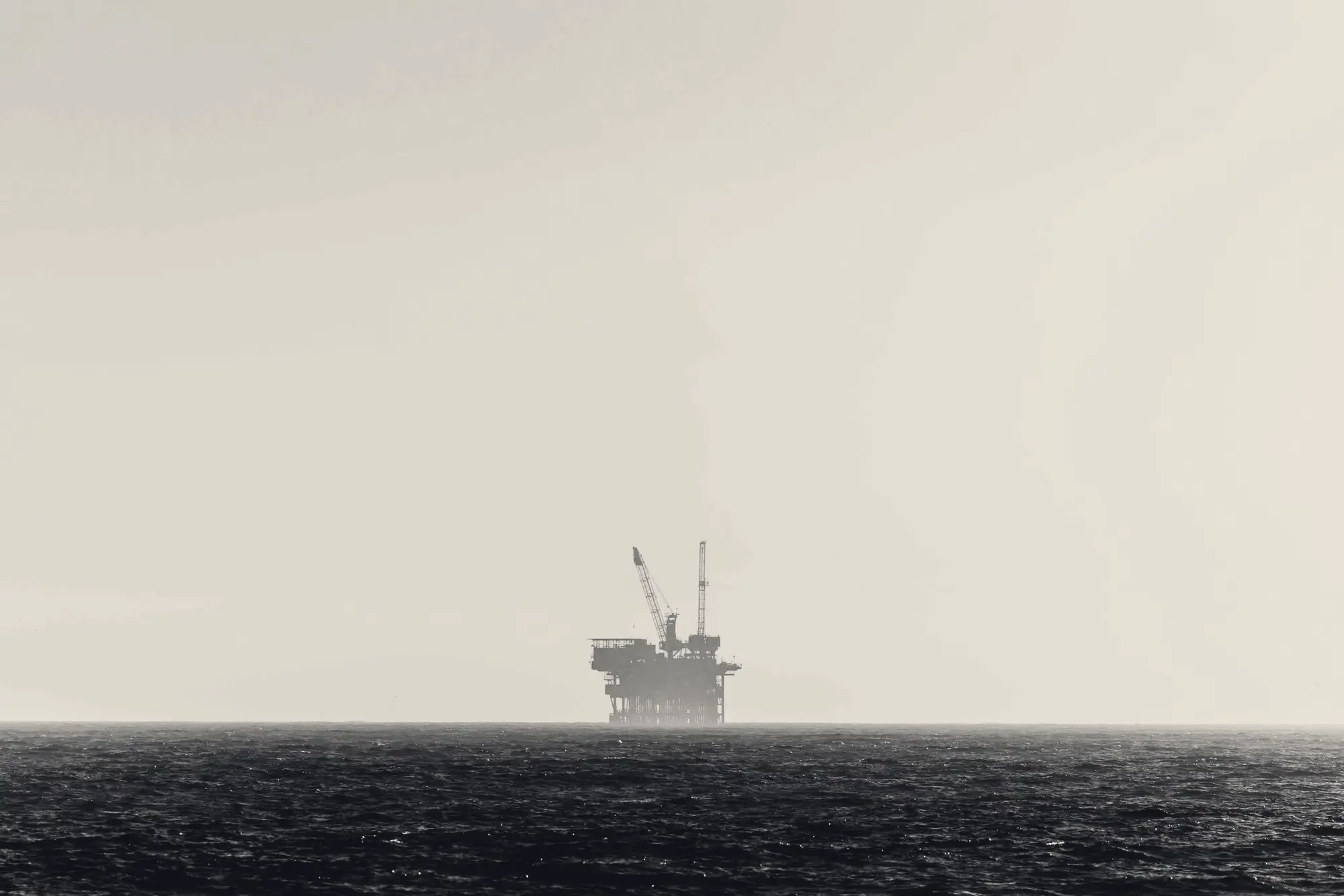Offshore oil platform at sunset over a calm sea